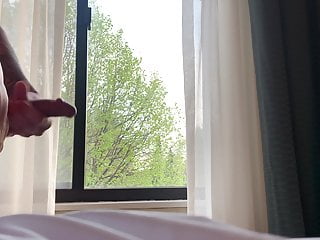 Jerking hard cock in hotel room window.
