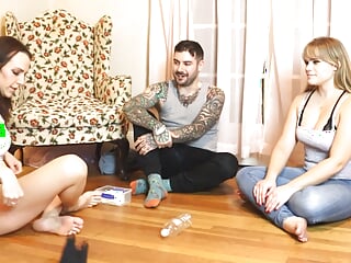 Two girls and one guy are playing a strip game of spin the bottle