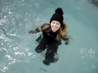 wetlook girl with winter clothes swims in the pool